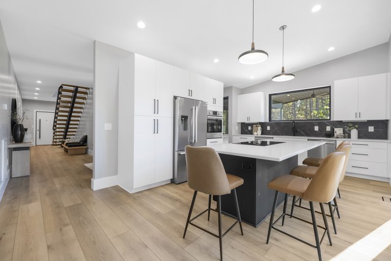 Modern kitchen with white cabinetry, stainless steel appliances, island with bar seating, and wood flooring